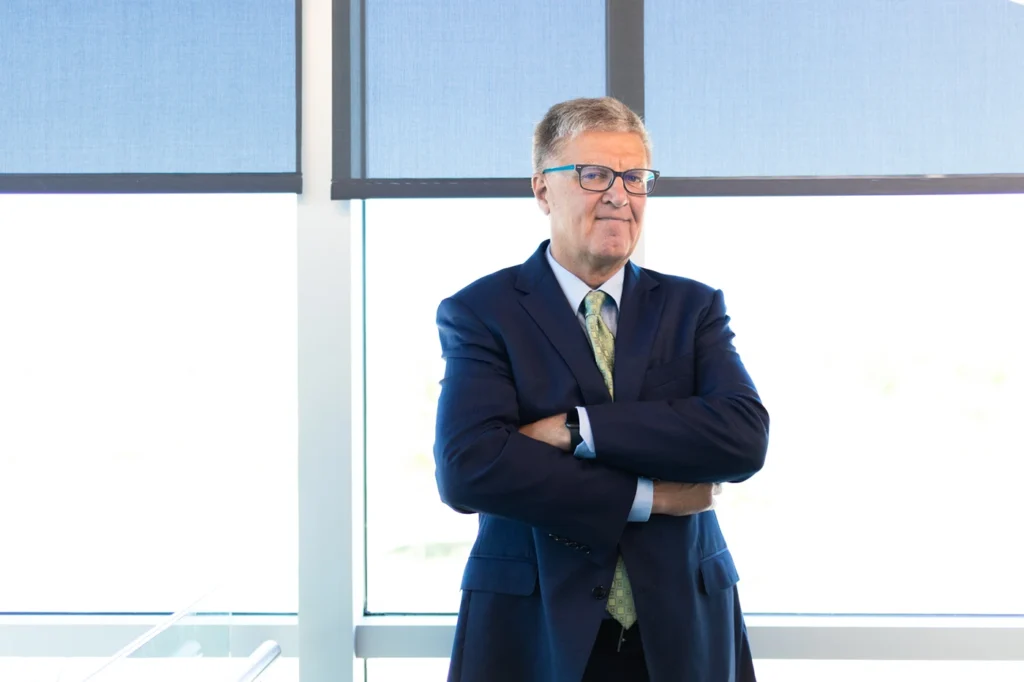 Harald Tomesch in blue suit in front of window